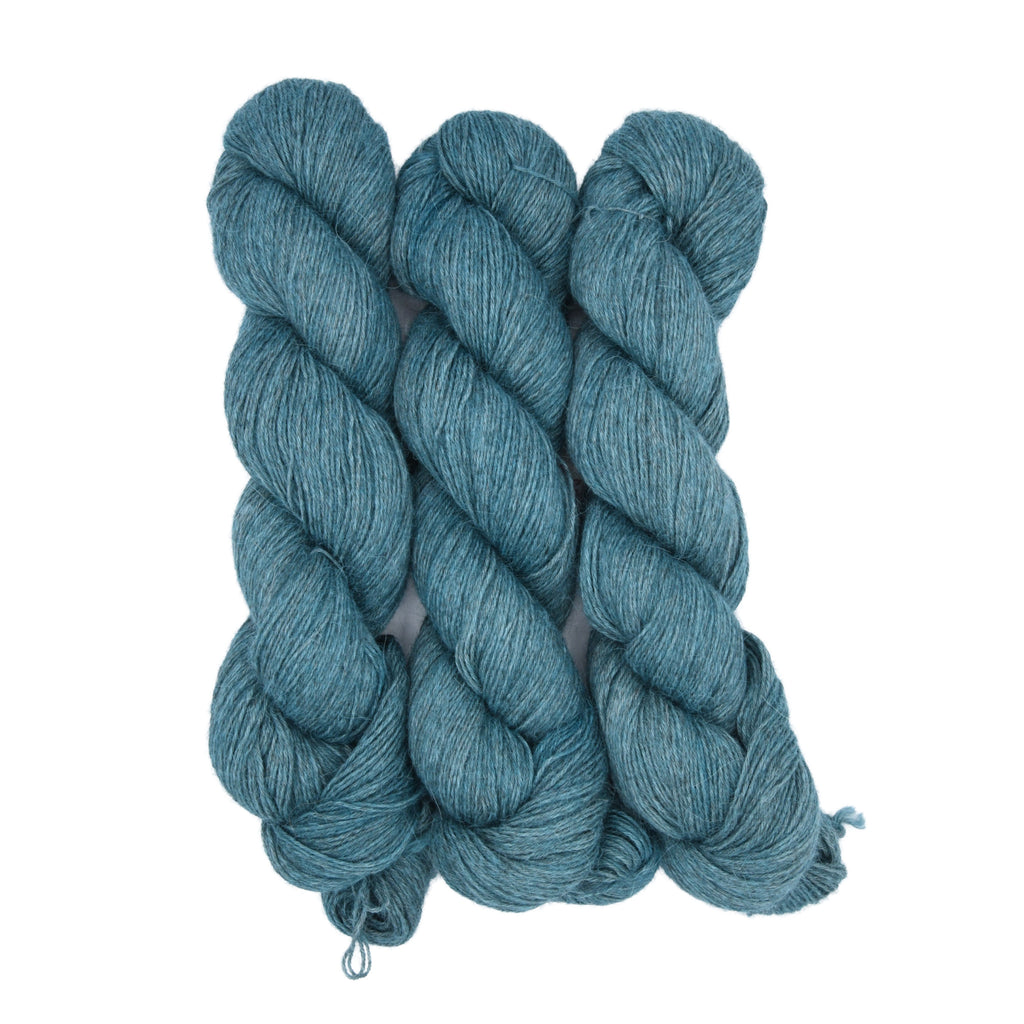 Woolly Headed Ideas fingering weight llama Hand dyed yarn skein in the Be More Pacific colorway featuring a soft light teal tone folded hanks with white background
