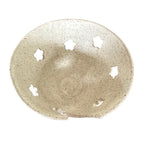 A handmade ceramic bowl with a speckled beige and white glaze, featuring five decorative cutouts on the inner rim, shown against a plain white background.