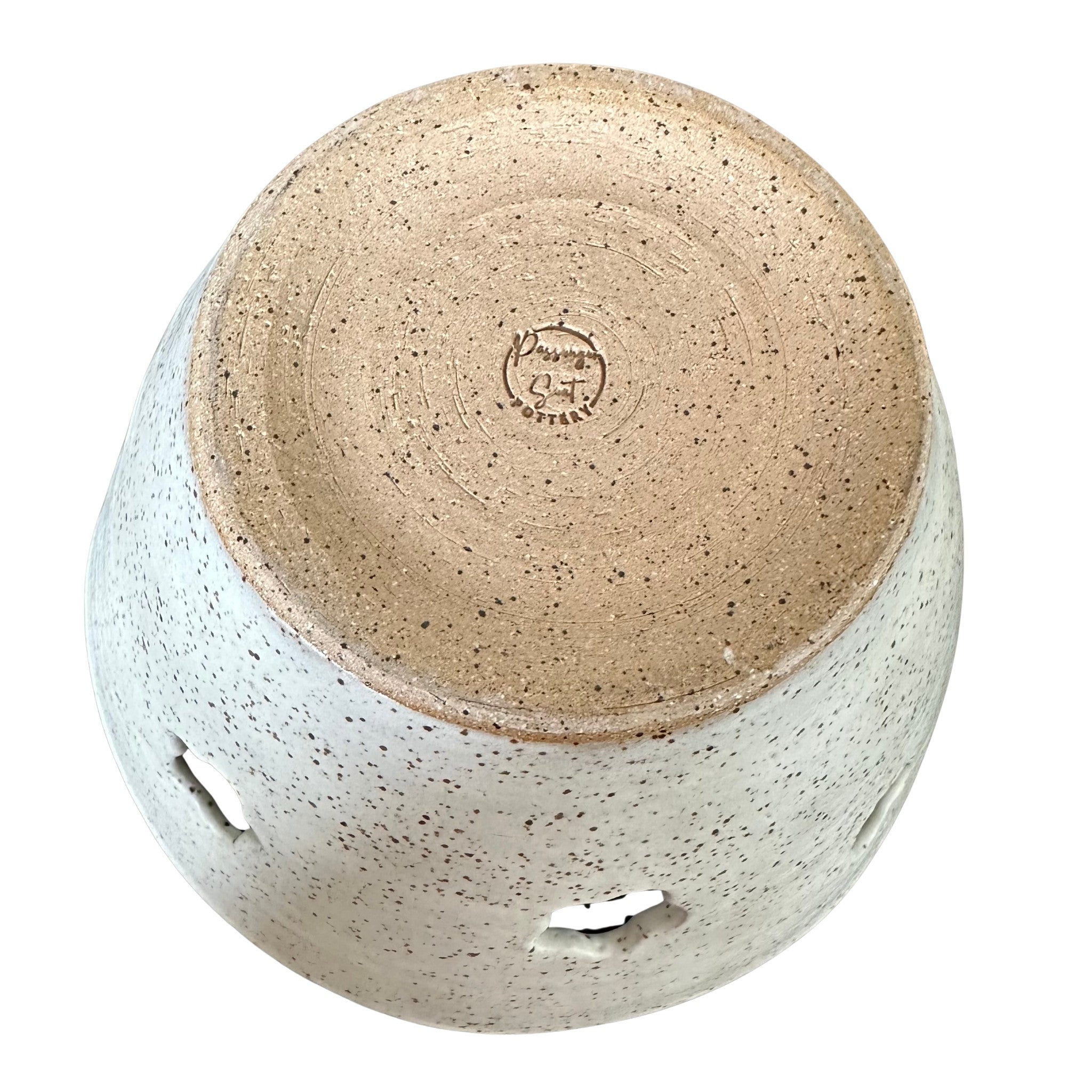 Bottom of a handmade ceramic yarn bowl from a top-down angle, featuring a speckled beige and white glaze with a natural brown clay bottom visible 