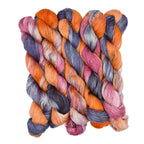 Multicolored yarn skeins braided together on a white background