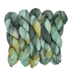Three skeins of green and gold yarn on a white background