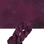 Woolly Headed Ideas fingering weight Llama Hand dyed yarn skein in the Can’t Beet Me! colorway featuring rich beet magenta and wine-toned hues.Two skeins of purple yarn on a gradient background