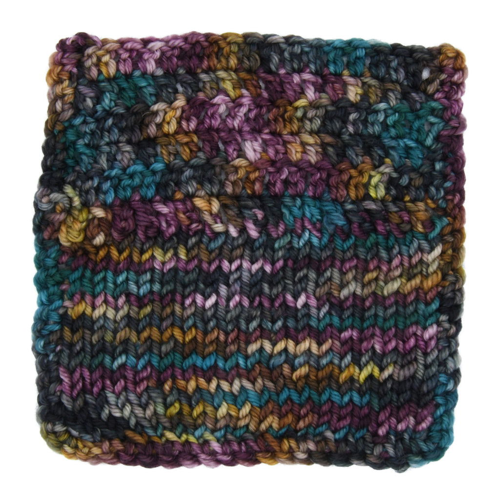 Knit and Crochet sample of Crown & Cloak hand-dyed yarn by Woolly Headed Ideas featuring a moody blend of black, dark gray, teal, green, olive, and a splash of gold.