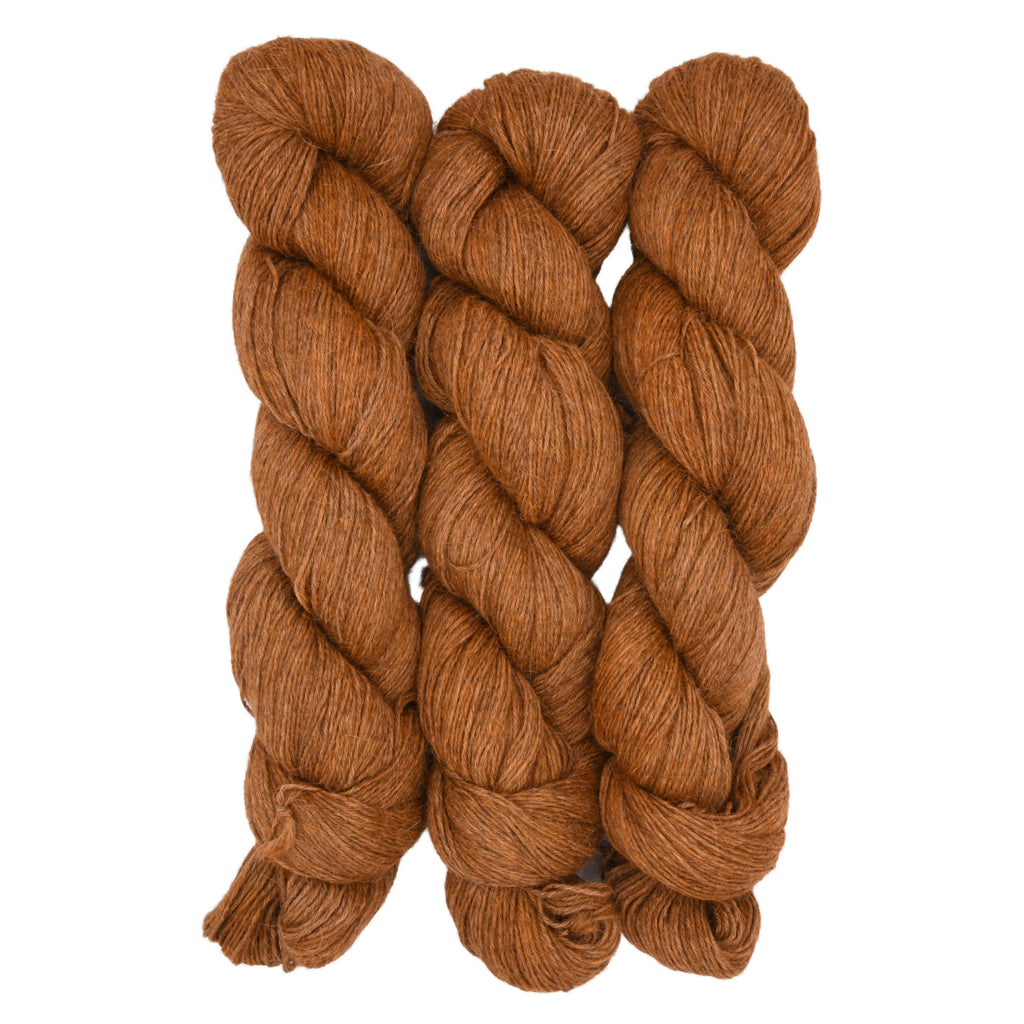 Three skeins of muted orange yarn on a white background