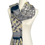 Knitted and crocheted Sampler Scarf with a geometric pattern on a mannequin against a white background