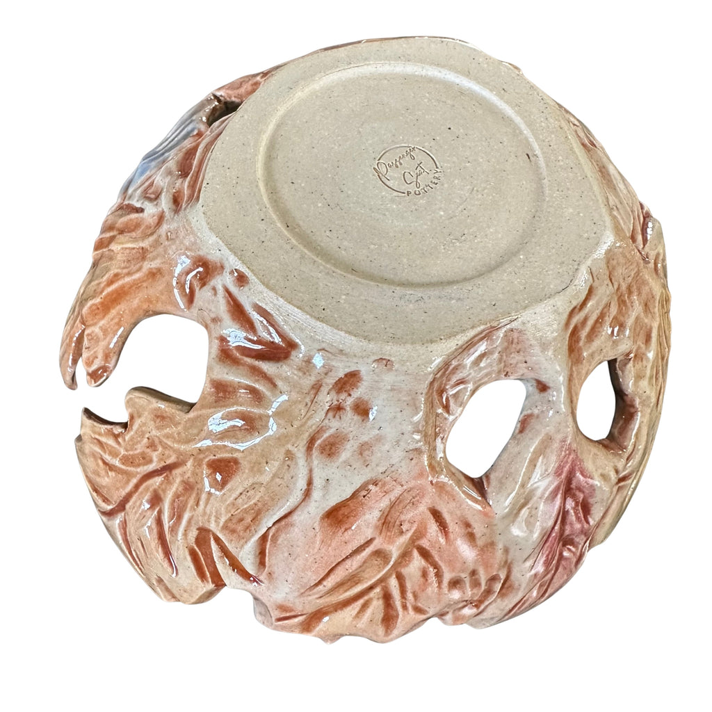 Bottom view of a ceramic yarn bowl featuring a textured, organic leaf exterior and large side cutouts, shown from a top-down view on a white background.
