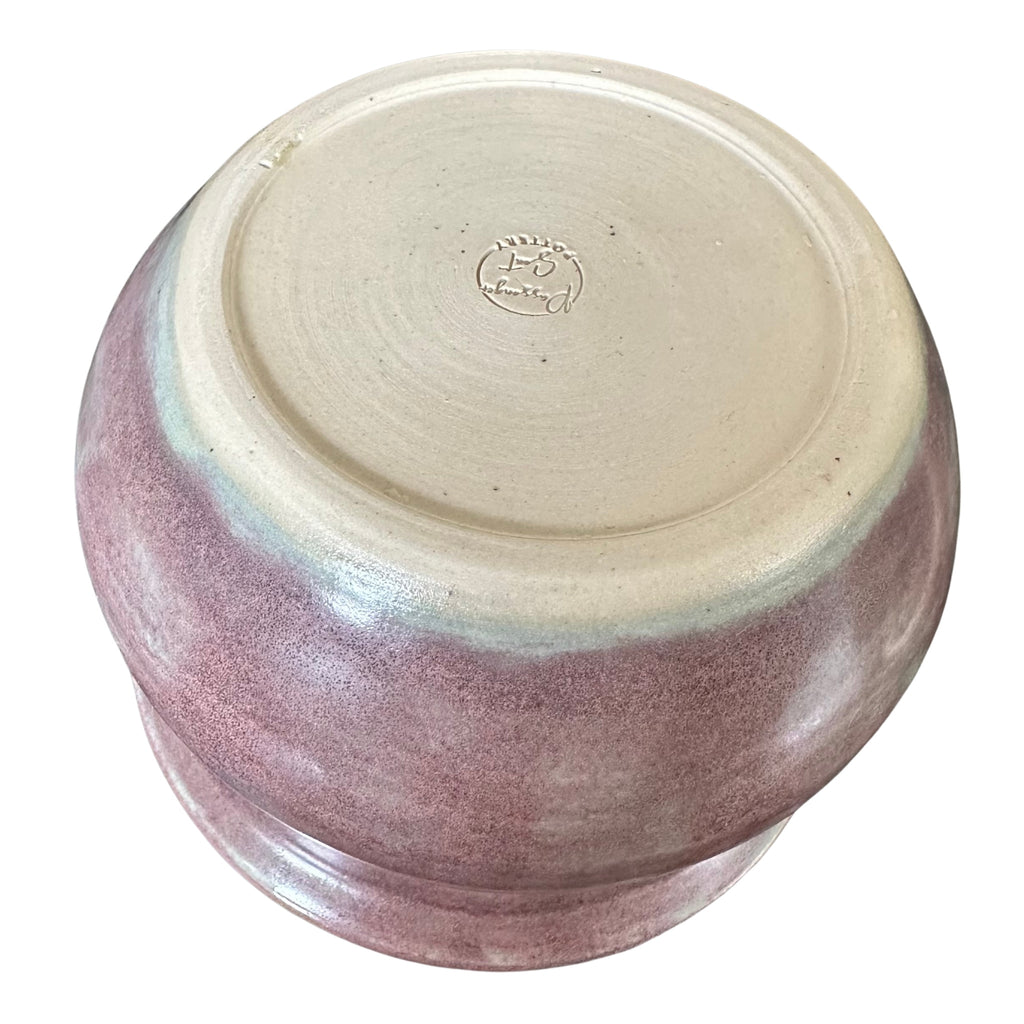 A round ceramic pot shown from a top-down angle, featuring a purple glaze on the sides and a smooth, unglazed light beige clay surface on the top.