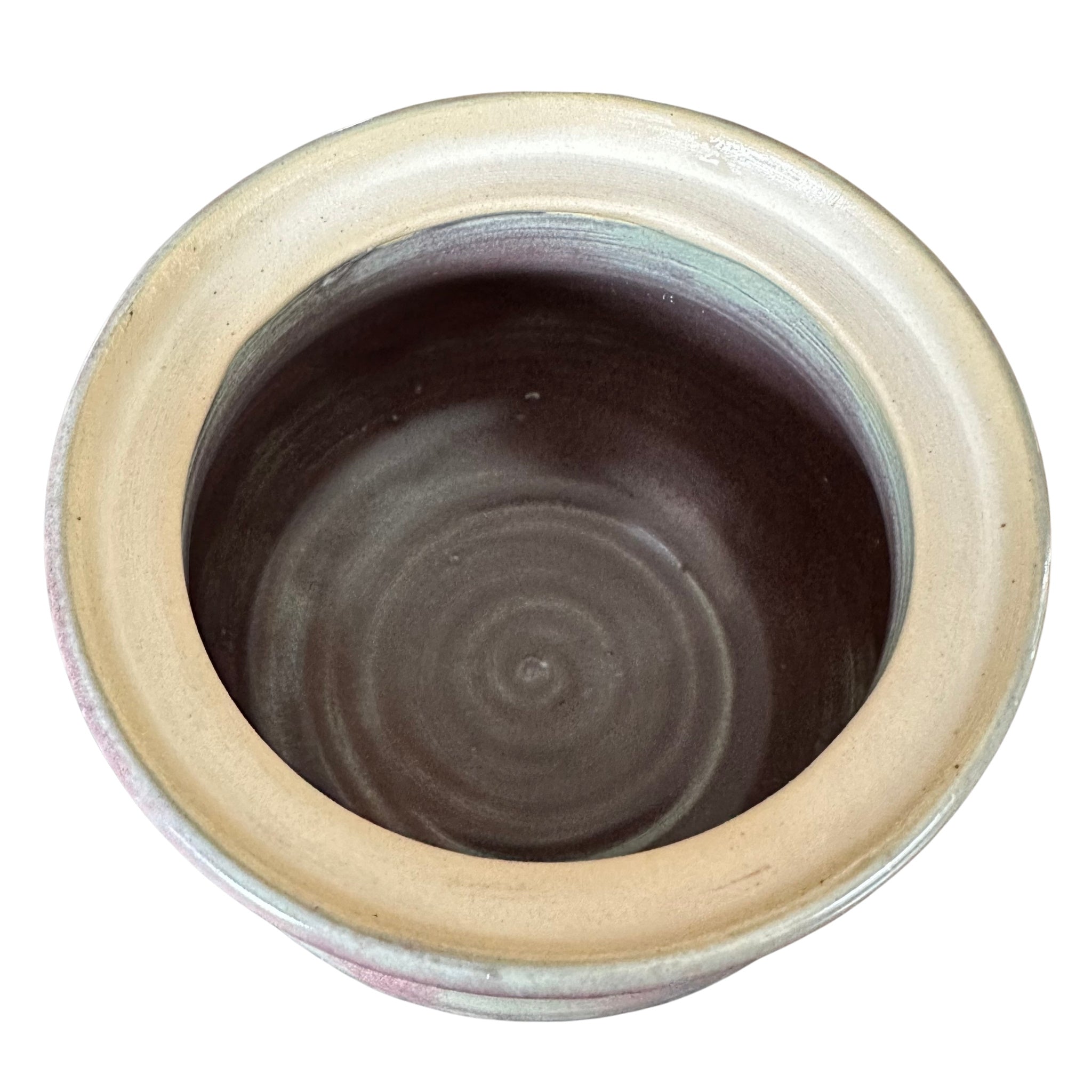 A handmade ceramic pot viewed from above, featuring a wide beige glazed rim and a purple interior with finger marks from throwing